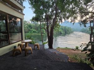 un tavolo e sedie accanto a una finestra con un fiume di Puprai Tarnnarm Resort a Thong Pha Phum
