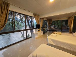 a bedroom with a bed and a large window at Puprai Tarnnarm Resort in Thong Pha Phum
