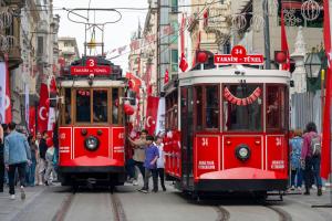 two red trolley cars on a city street with people at Pera Rose Hotel - Taksim Pera in Istanbul