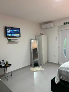Una habitación blanca con una cama y un televisor en la pared. en Apartments Indigo, en Jajce