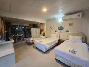 a hotel room with two beds and a dining room at Puprai Tarnnarm Resort in Thong Pha Phum