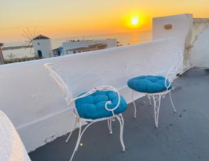 two chairs sitting on a balcony with the sunset at Sunset Queen in Oia in Oia