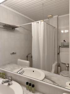 uma casa de banho branca com um lavatório e um chuveiro em Sidra Hotel em Hydra