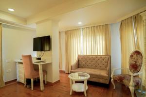 una camera d'albergo con divano, tavolo e scrivania di Hotel Magenta Jaipur a Jaipur