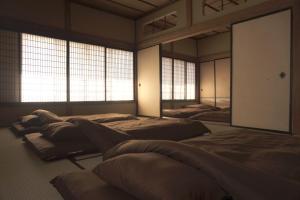 Zimmer mit 3 Betten und Fenstern in der Unterkunft Aioi Yanto 一日一組限定古民家宿 in Otaru