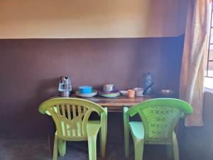 une table avec deux chaises et une table avec des assiettes et des tasses dans l'établissement Simoonga Thandizani School, à Livingstone