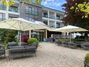 a patio with chairs and umbrellas in front of a building at Simon - das Vitalhotel in Bad Tatzmannsdorf