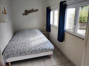 a small bedroom with a bed and two windows at La cabine en Baie de Somme in Cayeux-sur-Mer