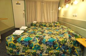 um quarto de hotel com uma cama com um edredão colorido em Lake Forbes Motel em Forbes