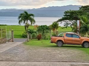 un camion arancione parcheggiato sull'erba vicino all'acqua di Sunset Lodge a Savusavu