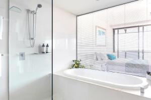 a white bathroom with a tub and a window at Sealuxe - Central Surfers Paradise -- Ocean View Deluxe Residences in Gold Coast