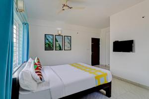 um quarto branco com uma cama e uma televisão em OYO Nr Royal em Bangalore