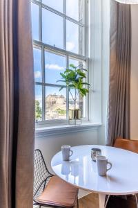 una mesa blanca y sillas frente a una ventana en No1 Apartments Edinburgh - George IV Bridge, en Edimburgo