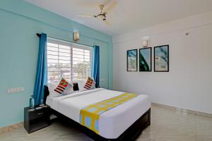1 dormitorio con 1 cama grande, paredes azules y ventana en OYO Nr Royal en Bangalore