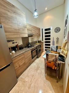 una cucina con armadi in legno, tavolo e lavastoviglie di Apparemment de luxe vue piscine a Bouznika