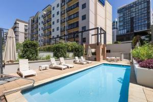 Una piscina con tumbonas y un edificio. en Mounts Bay Stay 2 Bedroom Apt - Near Kings Park - Free Parking, en Perth