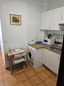 een keuken met een wastafel, een tafel en een wasmachine bij Apartamento Doble Exterior en la GRAN VIA de Madrid in Madrid