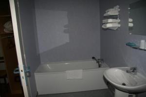 ein Badezimmer mit einer weißen Badewanne und einem Waschbecken in der Unterkunft Hotel Au Bon Sejour in Vitry-le-François