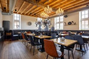 a restaurant with tables and chairs and chandeliers at Hotel De Boskar Peer in Peer