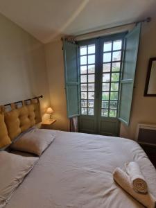 a bedroom with a large bed and a large window at Le Logis Saint Roch in Pézenas