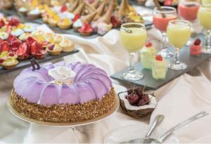 a table topped with a purple cake and other desserts at Grand Hotel Sunny Beach - All Inclusive in Sunny Beach +92 photos