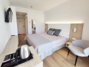 カラ・ラトハダにあるFlacalco Hotel & Apartmentsの小さなベッドルーム(ベッド1台、椅子付)