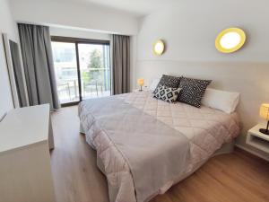 een slaapkamer met een groot bed en een groot raam bij Flacalco Hotel & Apartments in Cala Ratjada