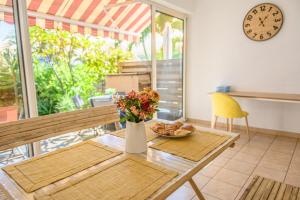a table with a vase of flowers and a clock at Le jardin des Tuit Tuit * Vue Mer * Cozy in Saint-Leu