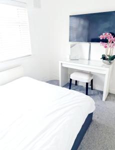 Un dormitorio con un escritorio blanco y una cama blanca. en 3 Bedroom House London, en Harrow