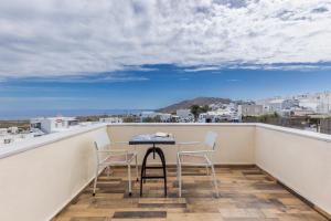 una mesa y sillas en un balcón con vistas al océano en UtopOia Apartment, en Oia