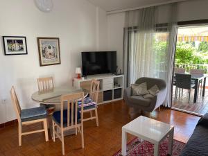 sala de estar con mesa, sillas y TV en Apartments Natasa, en Punat