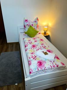 Una cama con una manta floral y almohadas. en Frühstückspension Elena Nicoleta Caltun en Fischamend Dorf