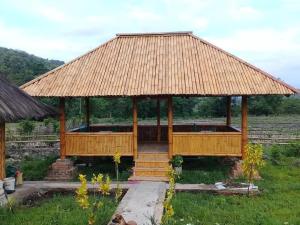 a bamboo pavilion with a grass roof on a field at Tado Homestay in Limbung