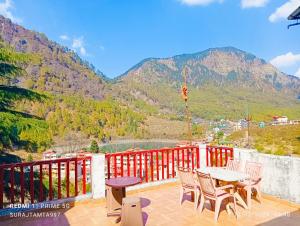un patio con mesa, sillas y montañas en Mansa Home Stay en Nainital