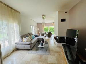 ein Wohnzimmer mit einem Sofa und einem TV in der Unterkunft Demeure familiale avec jardin, quartier calme in Anguerny