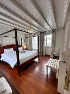 a bedroom with a canopy bed and a wooden floor at Le Coq Apartments in Mikonos