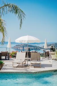 a pool with chairs and a table and an umbrella at Hôtel La Villa Douce in Rayol-Canadel-sur-Mer