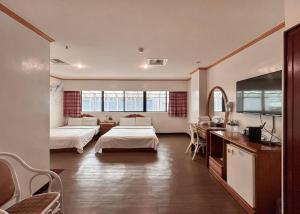 Habitación de hotel con 2 camas y TV de pantalla plana. en Tzu Chi Hotel en Pingtung City