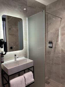 uma casa de banho com um lavatório branco e um chuveiro em OZO Hotels Antares Airport em Hoofddorp