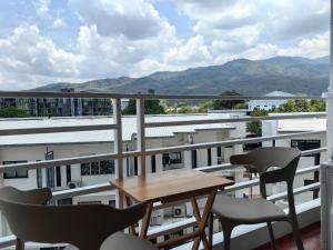 d'un balcon avec une table en bois, des chaises et des montagnes. dans l'établissement Mountain view & Quiet Cozy Condo, à Chiang Mai