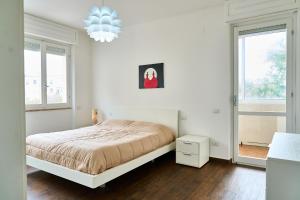 een witte slaapkamer met een bed en 2 ramen bij Casa Rosita in Carbonia