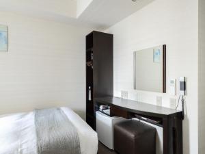 a bedroom with a desk with a bed and a mirror at Vessel Inn Hiroshima Ekimae in Hiroshima