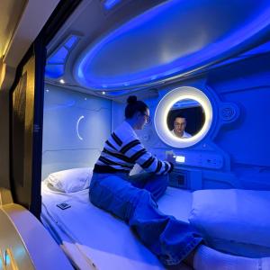 a woman sitting on a bed in a room with a mirror at Atypicap Capsule Hostel in Puerto de la Cruz