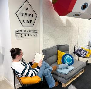 a woman sitting on a chair reading a book at Atypicap Capsule Hostel in Puerto de la Cruz +38 photos