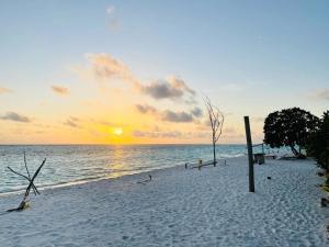 a sunset on a beach with the sun setting at Sunnyside Inn Thoddoo in Thoddoo