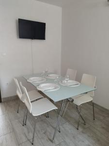 a table with white chairs and a television on a wall at ApartmanA&J1111 in Kaštela