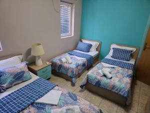 a room with three beds and a table with a lamp at Lion Apartment in Star Dojran