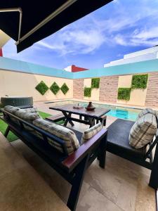 un patio con mesa, sillas y piscina en Villa de Luxe - Agadir City, en Agadir