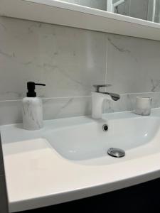 a white sink with two faucets and two cups on it at Villa Mirabelle 4 personnes in Châteauneuf-de-Gadagne +23 photos