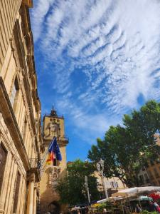 um edifício com uma torre de relógio e um céu nublado em Le Beffroi de Gaston em Aix-en-Provence